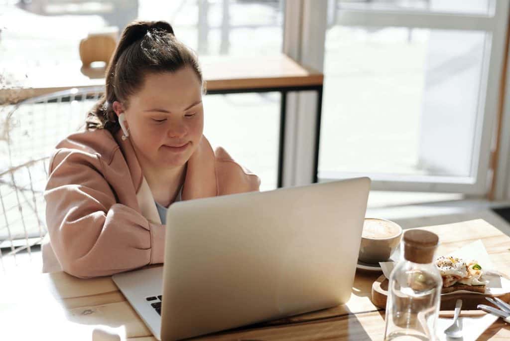 Adult girl with down syndrome talking on her laptop in virtual program