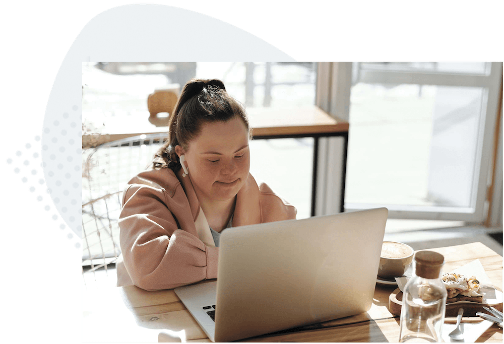 Adult girl with down syndrome talking on her laptop in virtual program