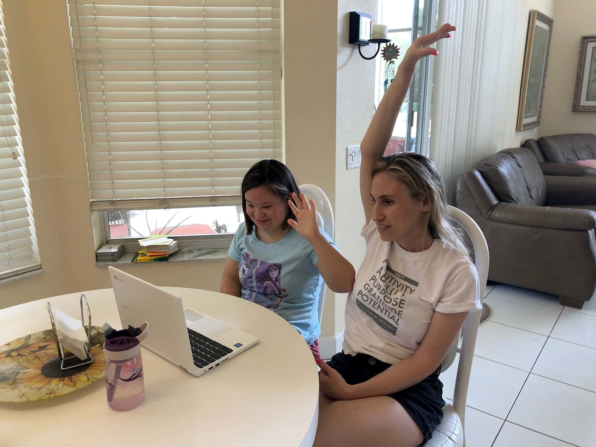 Two women sitting at a table with laptops in front of them.